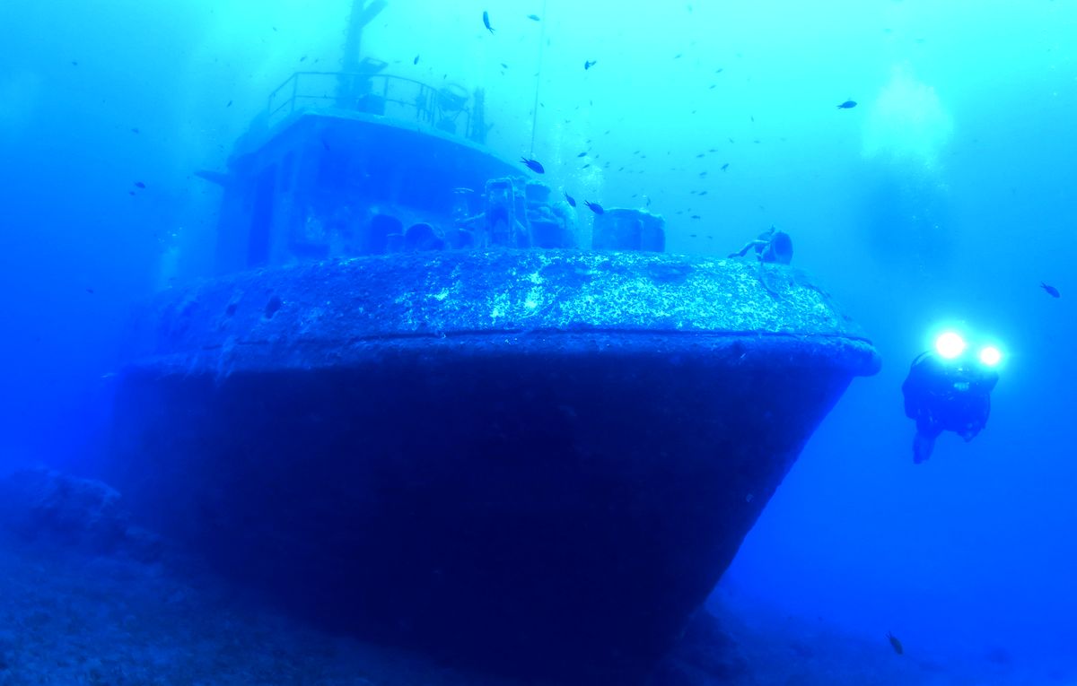 A diver with torches approaching the bow of the Constandis wreck off Limassol, Cyprus