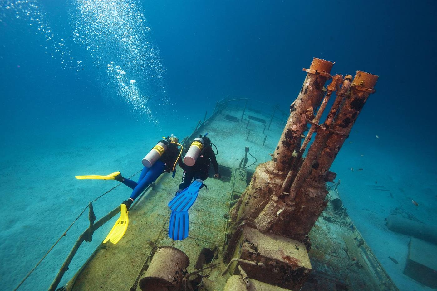 Two divers on enriched air finning over the deck of a sunken wreck