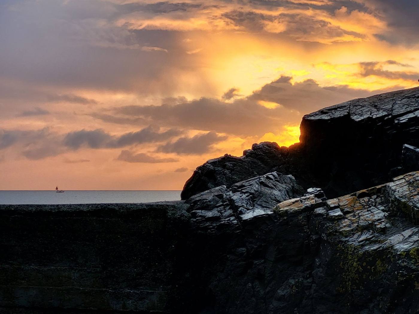 Sunset over the sea behind the rocks at Porthkerris, Cornwall